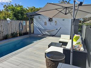 a patio with a table and an umbrella next to a pool at Our Retreat in Forster