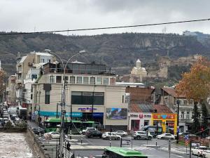 a city street with cars and buildings and a mountain at Golden Old Avlabari in Tbilisi City