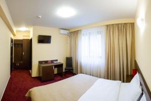 a hotel room with a bed and a desk at Hotel Athos in Bucharest