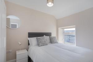 The Innkeeper’s Lodge Bushmills في بوشميلس: غرفة نوم بيضاء بها سرير ونافذة