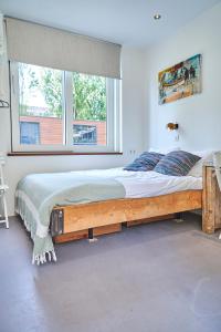 1 cama grande en un dormitorio con ventana grande en The Amsterdam Houseboat Family - de Pijp, en Ámsterdam