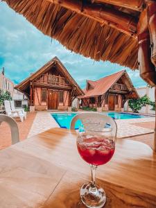 a glass of wine sitting on a table near a pool at Hostal Victoria Club A&C in Arboletes