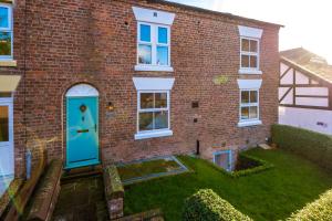 a brick house with a blue door and a yard at Ivy House Luxury Cheshire Cottage for relaxation. Chester Zoo· in Saughall