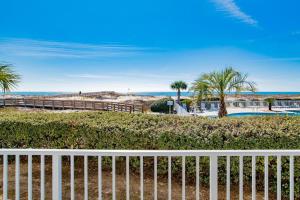 a white fence next to a beach with palm trees at Beachfront Stylish Condo - Stunning Views! in Gulf Shores
