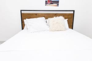 - un lit blanc avec une tête de lit en bois et des oreillers blancs dans l'établissement Yoyo Kunda, à Banjul