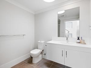 a white bathroom with a toilet and a sink at North Entrance Holiday Home in The Entrance +11 photos