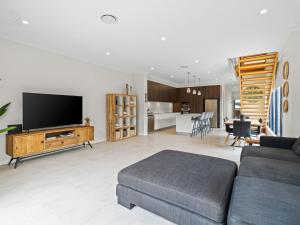a living room with a couch and a tv at North Entrance Holiday Home in The Entrance