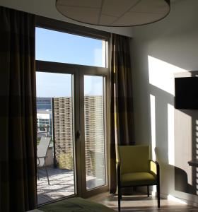 um quarto com uma cadeira e uma porta de vidro deslizante em Mondo hôtel em Tubize