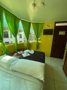 um quarto com uma cama com cortinas verdes em Hostal Maria Mercedes em Baños