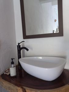 a white sink on a wooden counter with a mirror at Camino al Mar in Ipala