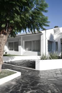 Una casa blanca con un árbol delante. en Casa Alsina en Chascomús