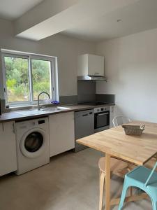 uma cozinha com uma máquina de lavar roupa e uma mesa em Appartement lumineux T2 avec terrasse et jardin em Calvi