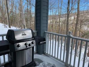 - un barbecue sur une terrasse couverte dans la neige dans l'établissement Chalet-Style Condo - 5 minutes to Lifts and village!, à Mont-Tremblant