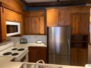 a kitchen with wooden cabinets and a stainless steel refrigerator at Chalet-Style Condo - 5 minutes to Lifts and village! in Mont-Tremblant