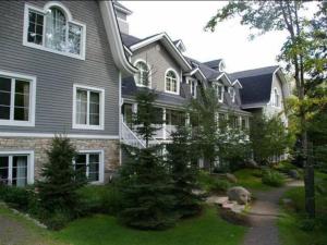 a large house with a garden in front of it at Chalet-Style Condo - 5 minutes to Lifts and village! in Mont-Tremblant