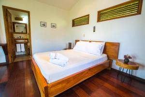 a bedroom with a bed with white sheets and a mirror at Verdad Nicaragua in San Juan del Sur