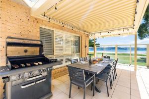 uma cozinha exterior com uma mesa e comodidades para churrascos em Sandy Beach House Corlette Unit 1 Waterfront WI-FI Aircon em Corlette