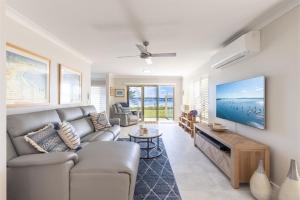 sala de estar con sofá y TV en Sandy Beach House Corlette Unit 1 Waterfront WI-FI Aircon, en Corlette