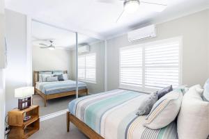 1 dormitorio con cama y espejo en Sandy Beach House Corlette Unit 1 Waterfront WI-FI Aircon, en Corlette