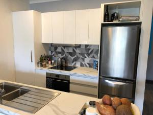 kuchnia z lodówką ze stali nierdzewnej i talerzem chleba w obiekcie Cool Apartment, Central To Everything, share with 2x Bulldogs w Auckland