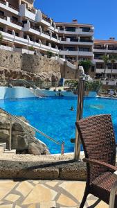 a chair next to a swimming pool with blue water at Sweet home ocean golf resort in San Miguel de Abona