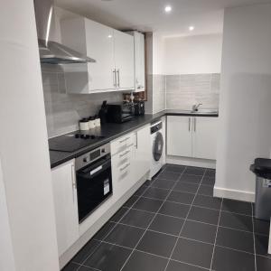 a kitchen with white cabinets and a black appliance at Classic 2 bed apartment in oldkent road in London