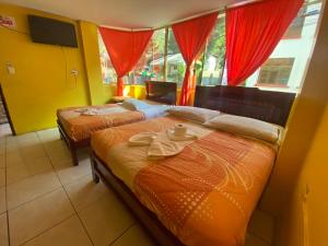 2 camas en una habitación con cortinas rojas en Hostal Maria Mercedes, en Baños