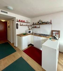 une cuisine avec des placards blancs et un tapis rouge et vert dans l'établissement Miti's House, à Sestrières