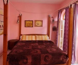 - une chambre avec un lit dans une chambre rose dans l'établissement Dar Alouane, à Essaouira