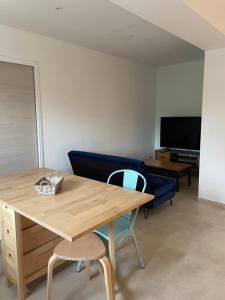 - un salon avec une table en bois et un canapé bleu dans l'établissement Appartement lumineux T2 avec terrasse et jardin, à Calvi