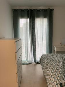 um quarto com uma cama e uma grande janela em Appartement lumineux T2 avec terrasse et jardin em Calvi