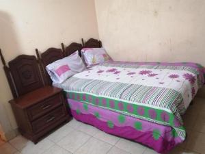 een slaapkamer met een bed en een houten nachtkastje bij pension de fer in San Luis Potosí