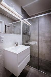 La salle de bains est pourvue d'un lavabo blanc et d'une douche. dans l'établissement Ottimo Apartamenty Floriana, à Bydgoszcz