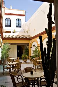 Hotel Barrameda في سانلوكار دي باراميدا: فناء في الهواء الطلق مع طاولات وكراسي ومبنى
