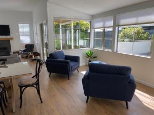 un salon avec un canapé, des chaises et une table dans l'établissement Gold Rush Cottage - Arrowtown Holiday Home, à Arrowtown