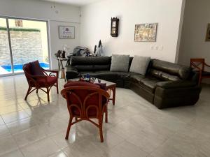 uma sala de estar com um sofá de couro preto e cadeiras em FRIDA'S Home Sol A em Puerto Morelos
