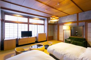 a hotel room with two beds and a television at Ryokan Yoshidaya in Ureshino