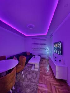 een woonkamer met paarse verlichting en een bank bij Apartman VUČKO in Pale