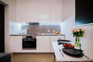 a kitchen with white cabinets and a table with flowers at Ottimo Apartamenty Dolina in Bydgoszcz