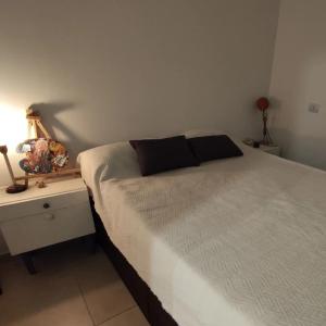 a bedroom with a white bed and a night stand with a lamp at Bauhaus departamento centro in Córdoba