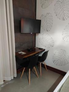 a desk with two chairs and a monitor on it at Pousada Sítio Vale das Olivas in Aiuruoca