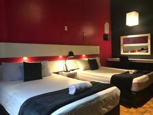 duas camas num quarto de hotel com paredes vermelhas em Hostal Regina Down Town Mexico City em Cidade do México