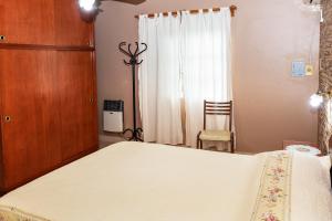 - une chambre avec un grand lit blanc et une chaise dans l'établissement Lo de Hilda, à Villa Elisa