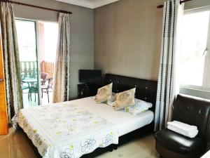 a bedroom with a bed and a chair and windows at Haji Hassan Guesthouse in Pantai Cenang