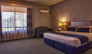 una habitación de hotel con una cama grande y una silla en Desert Cave Hotel, en Coober Pedy