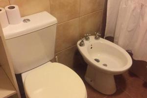 La salle de bains est pourvue de toilettes blanches et d'un lavabo. dans l'établissement La Joaquina, Casa de montaña., à El Chalten