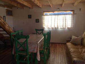a dining room with a table and chairs and a couch at La Joaquina, Casa de montaña. in El Chalten