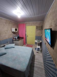1 dormitorio con cama y puerta amarilla en Kitnet Barra de Ibiraquera, en Barra de Ibiraquera