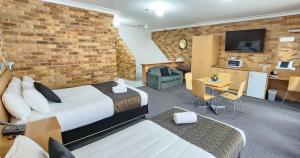 a hotel room with a bed and a brick wall at Golf Club Motor Inn Wingham in Wingham