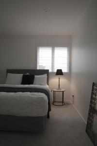 1 dormitorio con 1 cama y 1 mesa con lámpara en TreeTops en Auckland
